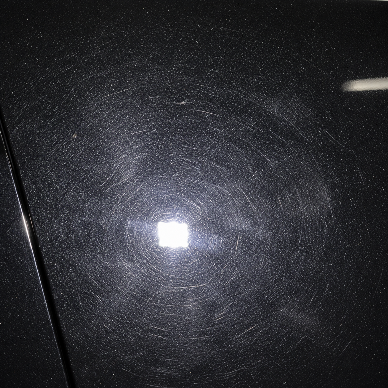 Black paint before correction, with visible swirl marks around the light